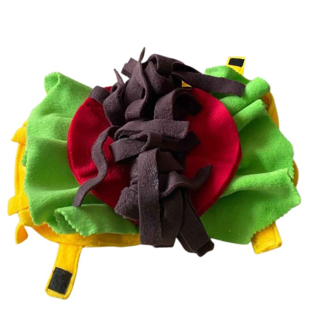 A colour image of a handmade dog toy in the style of a taco. It is made from yellow, green, red and brown fleece fabric and opens to lay flat or close.